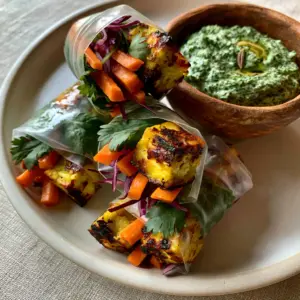High-angle shot of translucent Indian rice paper rolls filled with golden paneer cubes and colorful julienned vegetables.